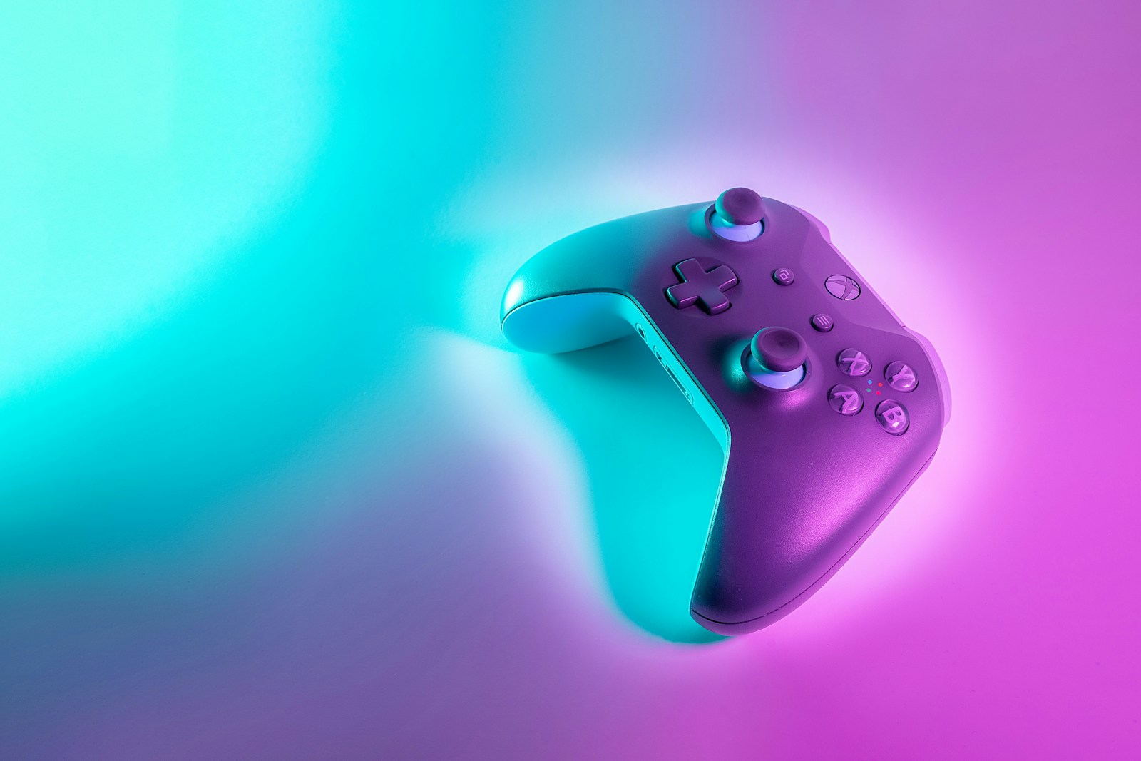 Wireless game controller illuminated by cyan and magenta light.