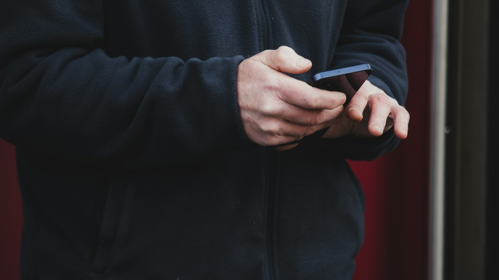 A person holding and using a smartphone outdoors.