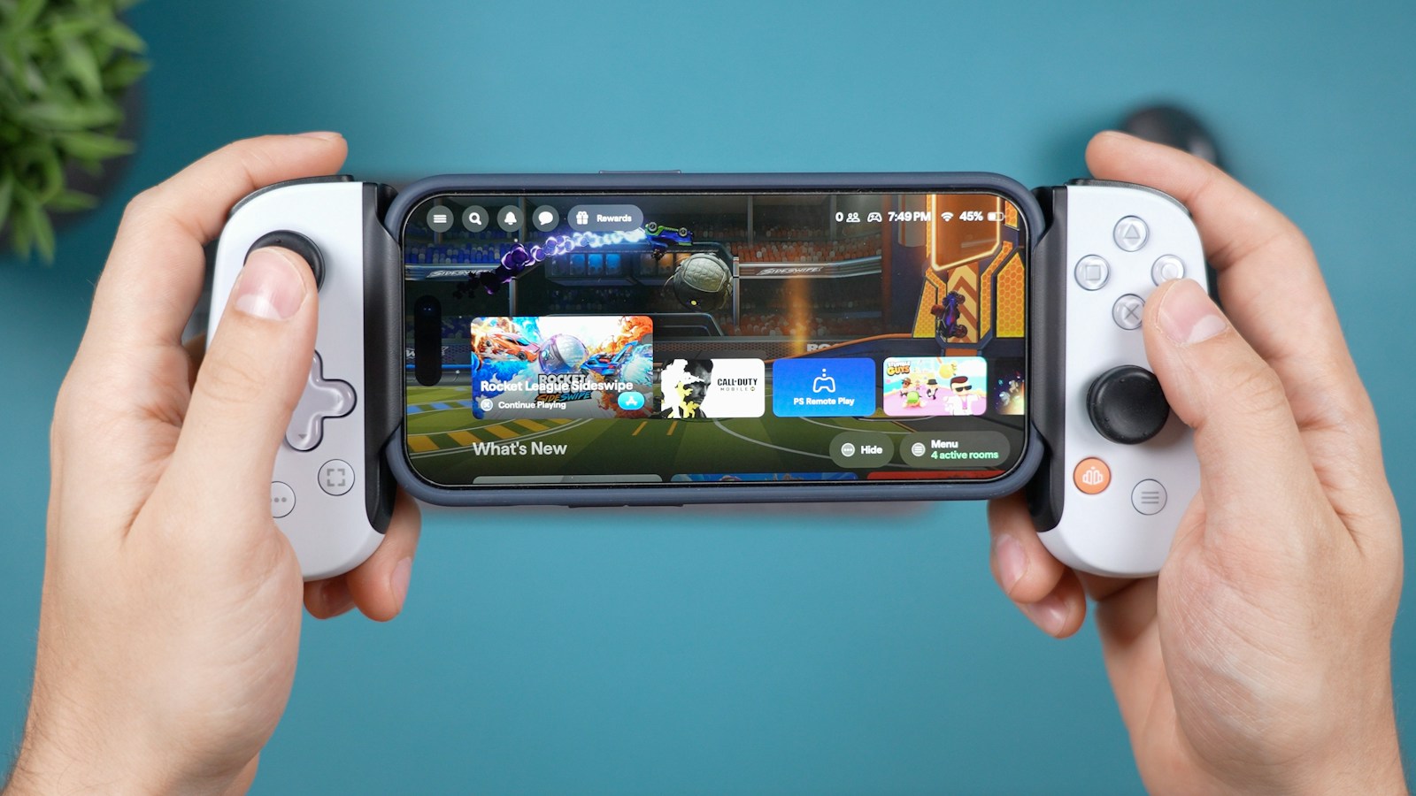 Hands holding a smartphone fitted with a gaming controller.