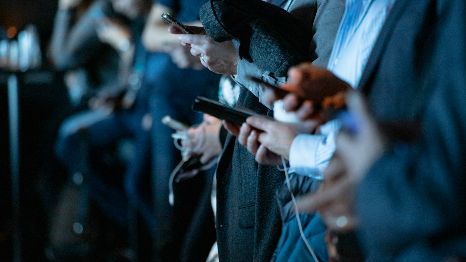 People standing together while using their smartphones.