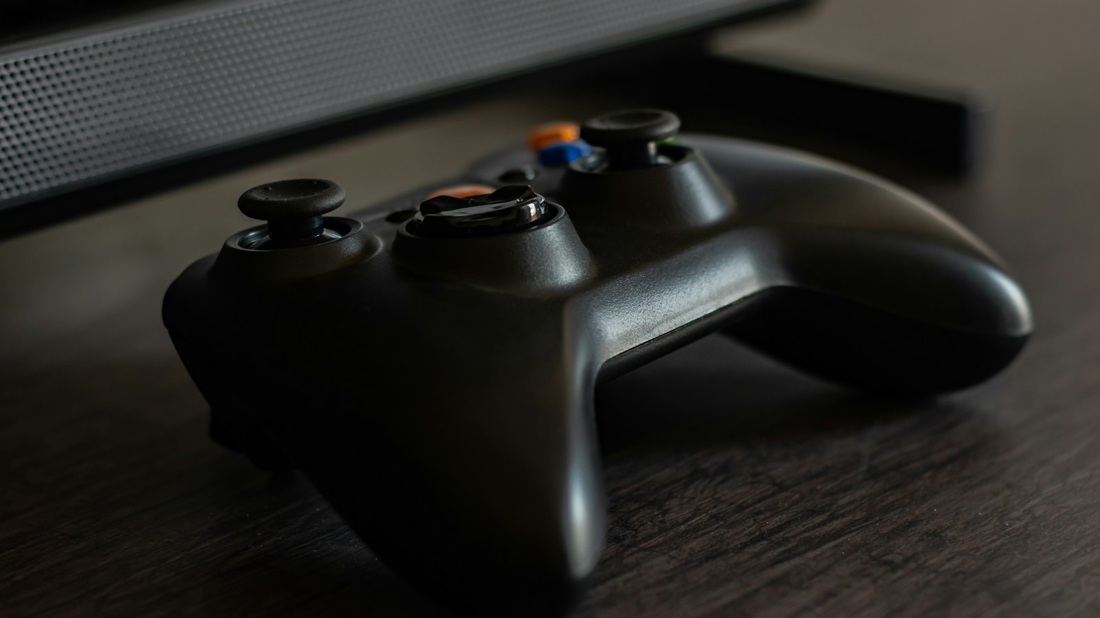 A black Xbox controller resting on a wooden table.